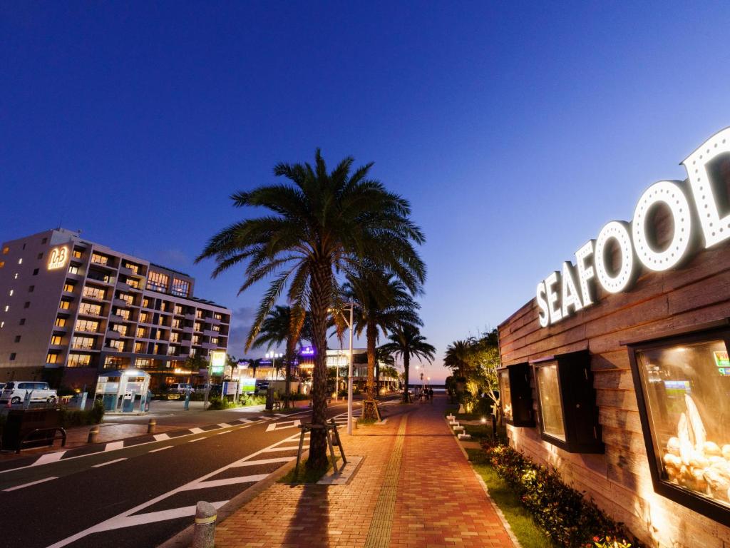 a city street with a palm tree and a building at MB GALLERY CHATAN by THE TERRACE HOTELS in Chatan
