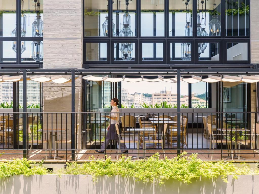 a woman walking on a balcony of a building at MB GALLERY CHATAN by THE TERRACE HOTELS in Chatan