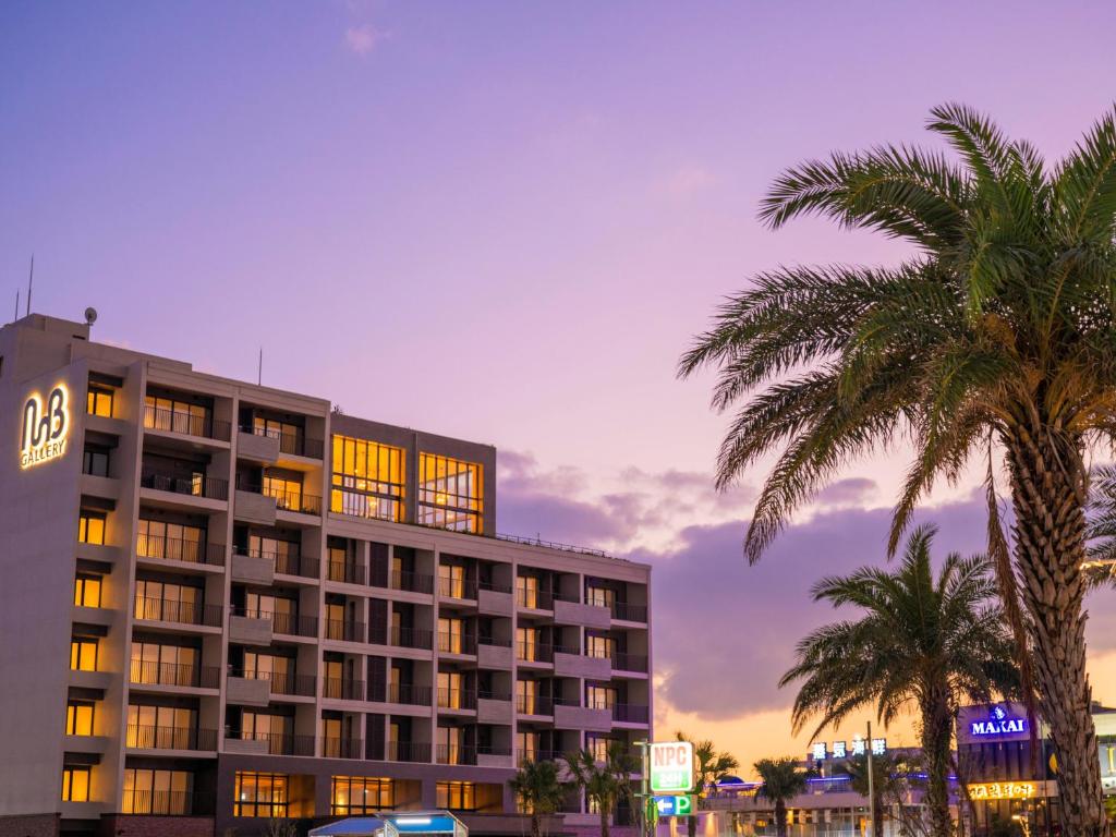 a hotel with palm trees in front of a building at MB GALLERY CHATAN by THE TERRACE HOTELS in Chatan