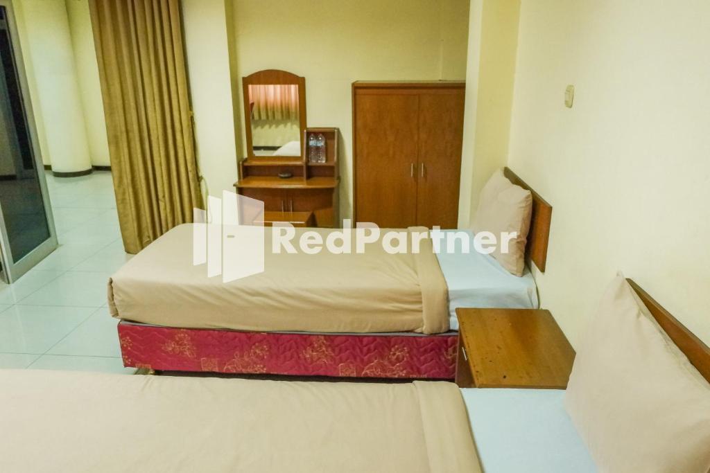 Postel nebo postele na pokoji v ubytování Grand Kembar Hotel Mitra RedDoorz