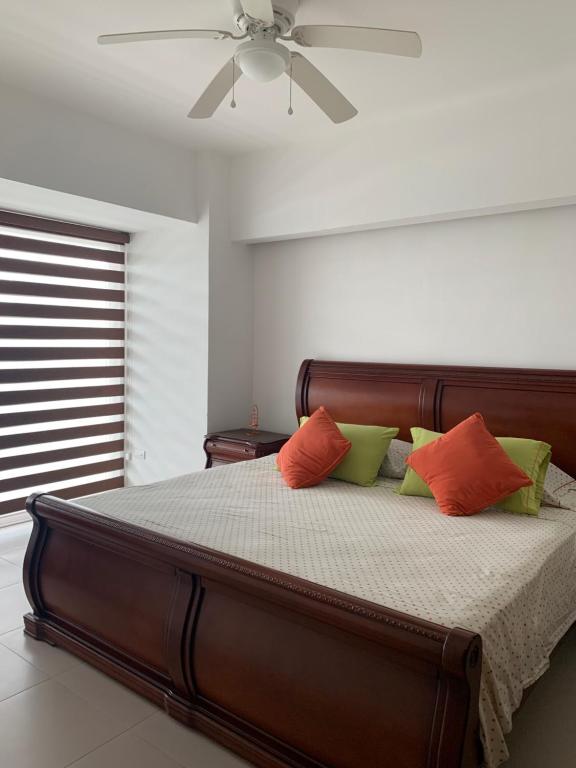 a bedroom with a bed with orange and green pillows at Suite de Lujo en Resort Playa Azul, Tonsupa in Tonsupa