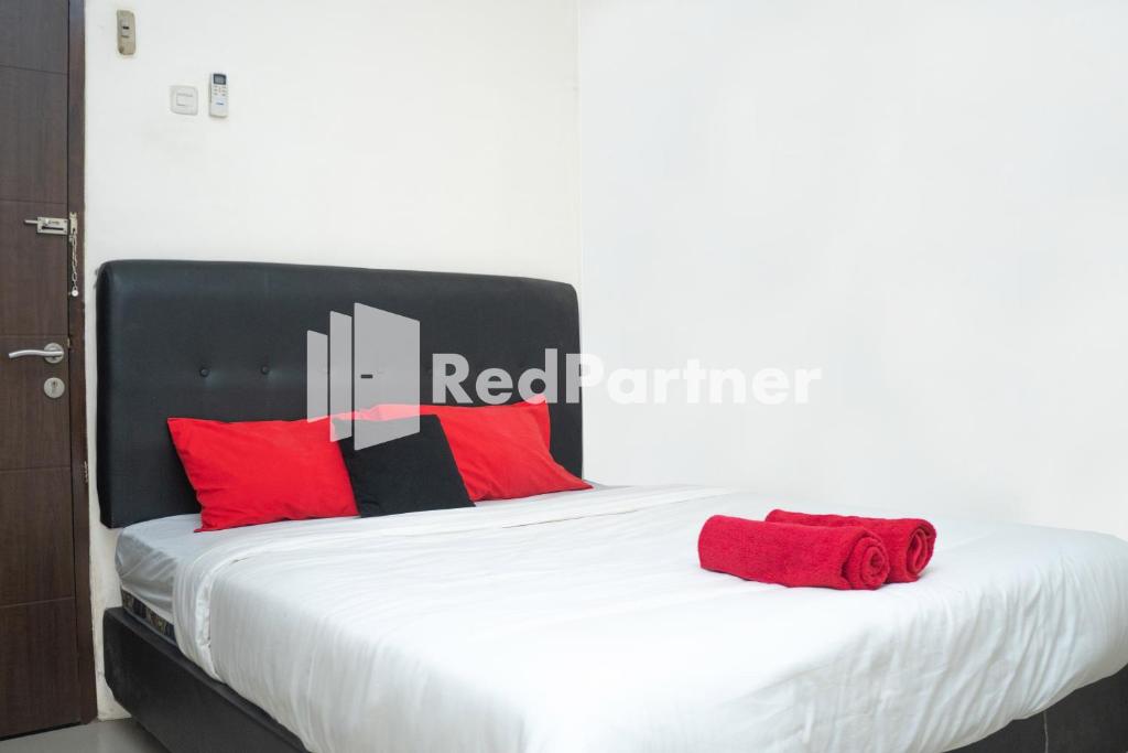 a bedroom with a bed with red pillows at Jabrix Hotel Mitra RedDoorz in Bandung