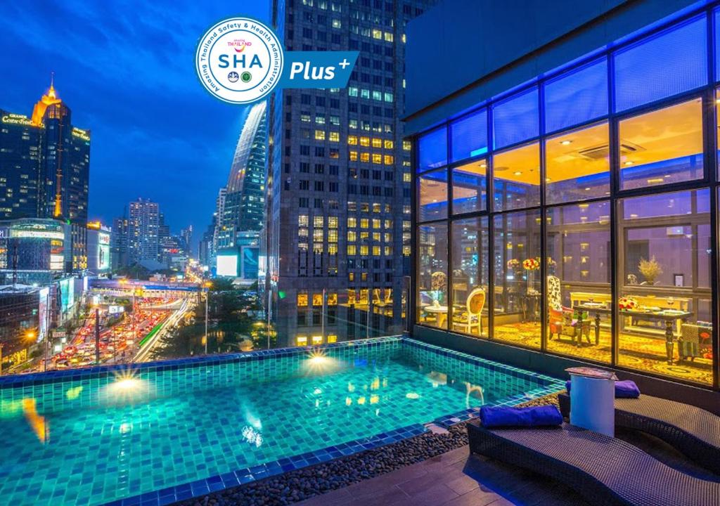a swimming pool on the roof of a building with a city skyline at Hotel Clover Asoke - SHA Extra Plus in Bangkok