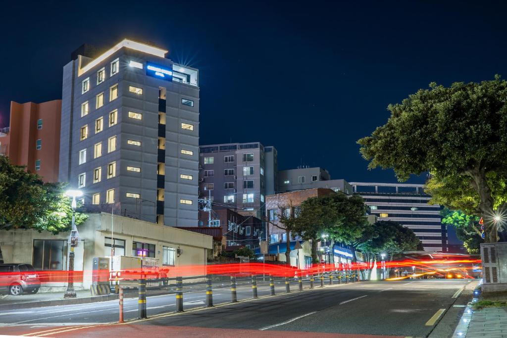 una strada di città di notte con un palazzo alto di Cornerstone Hotel a Seogwipo