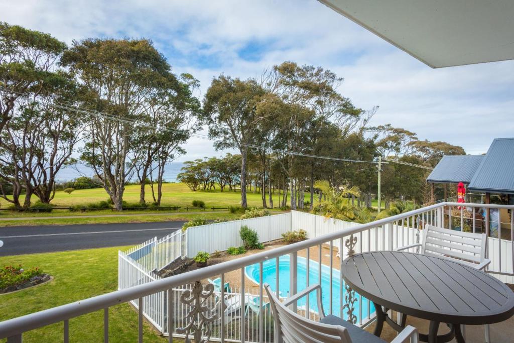 a balcony with a table and chairs and a pool at Views on Ballingalla in Narooma