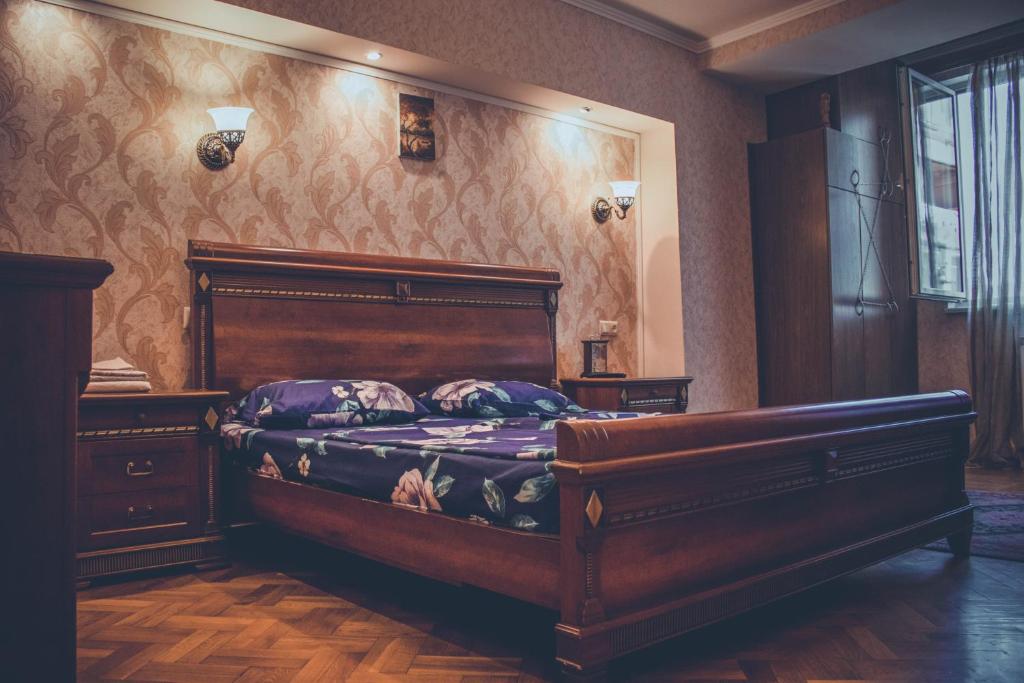 a bedroom with a bed with a wooden headboard at Apartment on Tumanyan Street in Yerevan
