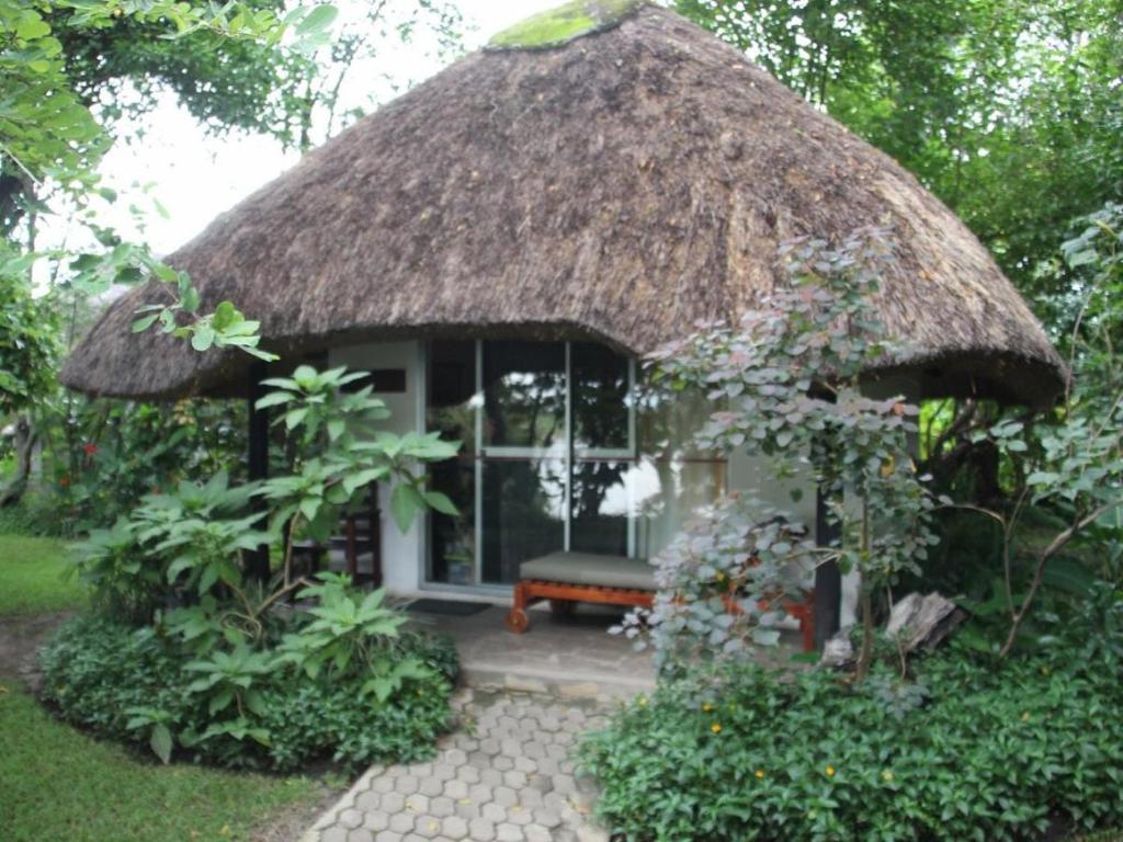 卡蒂馬穆利洛的住宿－Caprivi River Lodge，茅草屋顶的小房子,里面设有长凳