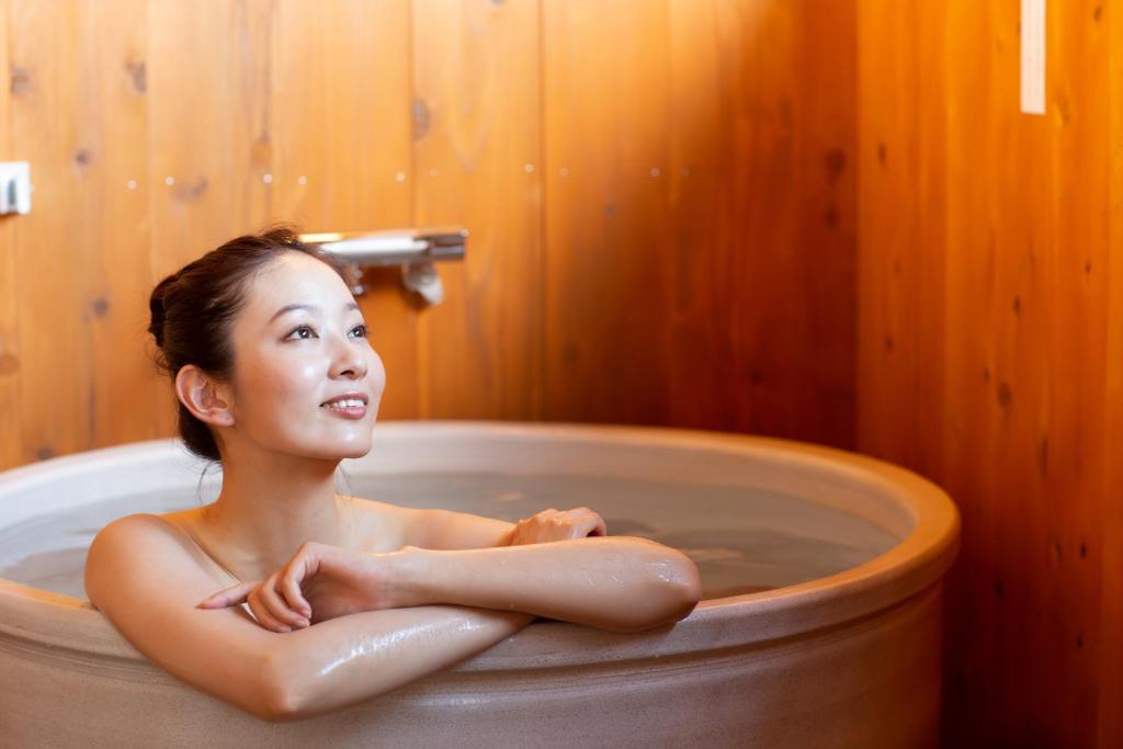 a woman is sitting in a bath tub at Kawaguchiko Country Cottage Ban in Fujikawaguchiko