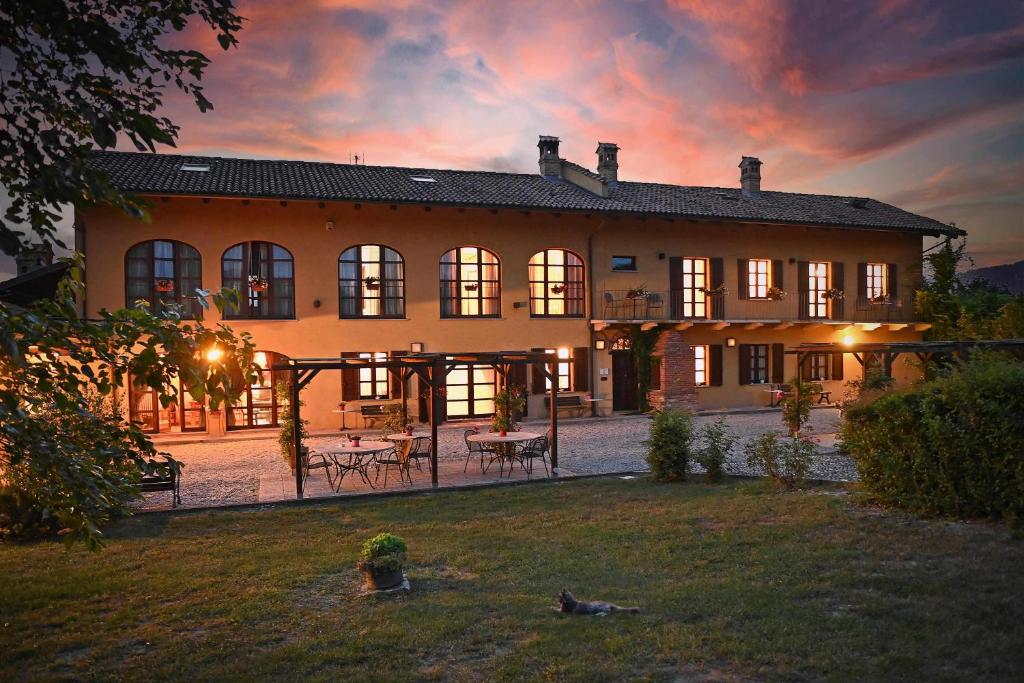 a large house with a sunset in the background at La Cà dOlga in La Morra