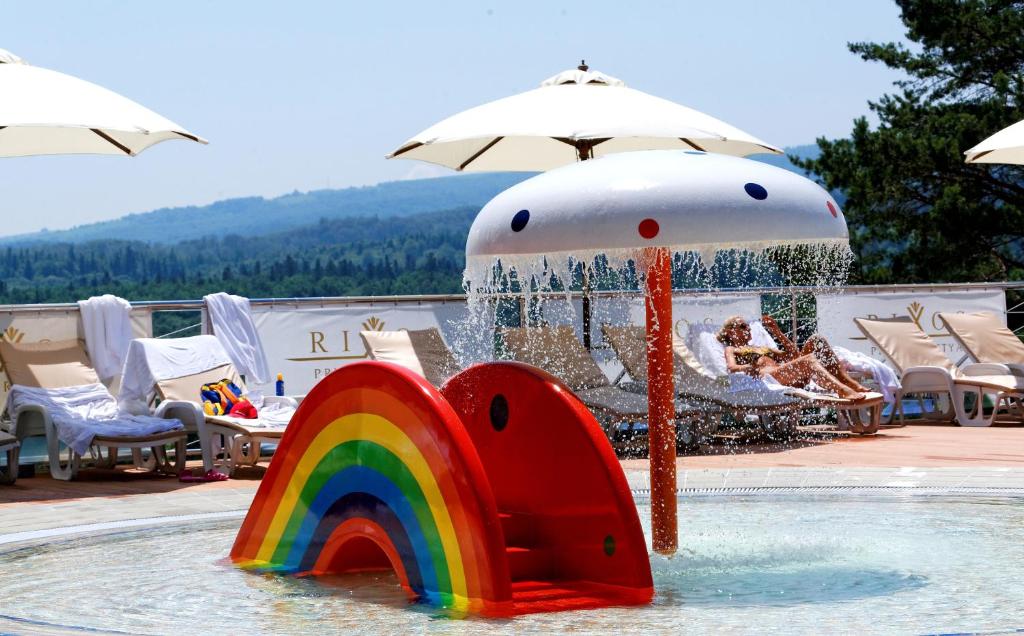 a pool with a rainbow in the water with an umbrella at Rixos-Prykarpattya Resort in Truskavets