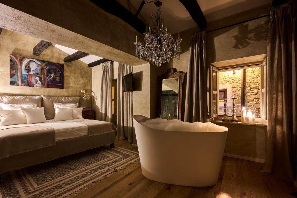 a bedroom with a tub and a bed and a chandelier at Casa Ars Natura II in Grožnjan