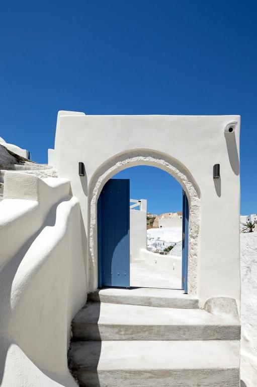 a stairway leading to a blue door in a building at Acave Santorini Suites in Vóthon