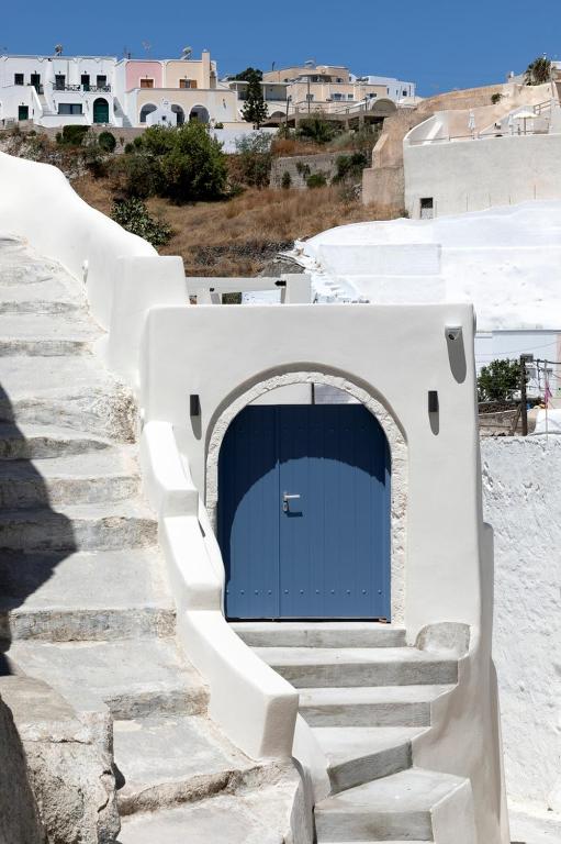 a blue door on a white building with stairs at Acave Santorini Suites in Vóthon