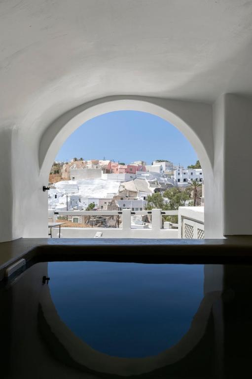 a room with a window with a view of a city at Acave Santorini Suites in Vóthon