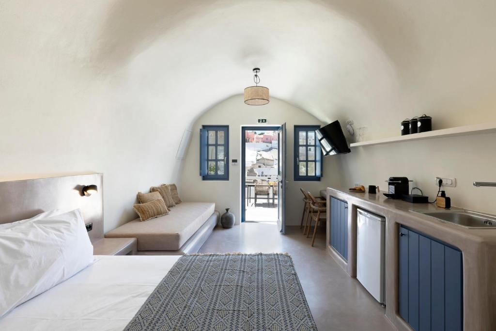 a room with a bed and a kitchen with a couch at Acave Santorini Suites in Vóthon