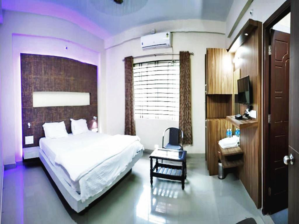 SringeriにあるSTAYMAKER Shubhodaya Lodgeのベッドルーム1室(ベッド1台、椅子、デスク付)