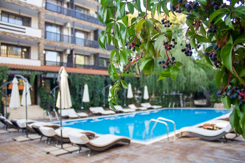 a pool with chairs and umbrellas next to a building at The Green Paradise Apartments in Primorsko