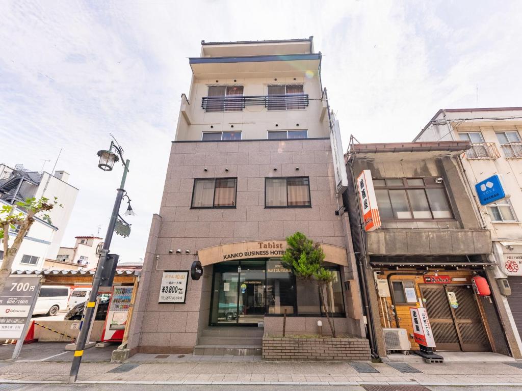 a tall building on the corner of a street at Tabist Kanko Business Hotel Matsuyama Hida Takayama in Takayama