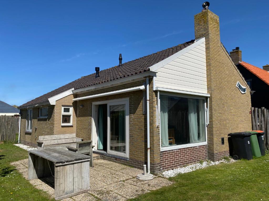 una casa con un banco en el patio en Op 't Landtweg 37, en Callantsoog