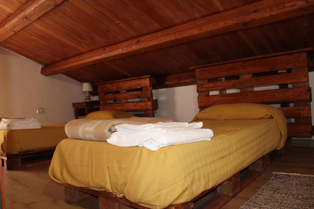 2 łóżka w pokoju z drewnianym sufitem w obiekcie Ospitalità diffusa Jungi Mundu w mieście Camini