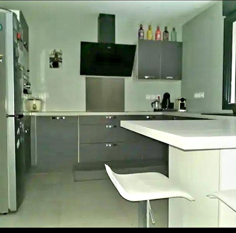 uma cozinha branca com um balcão branco e um frigorífico em Chambre privée dans maison em Le Tampon