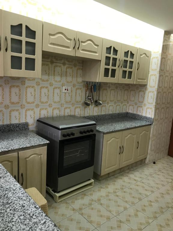 a kitchen with white cabinets and a black stove at Maliaways Comfy Airbnb-Jkia in Nairobi