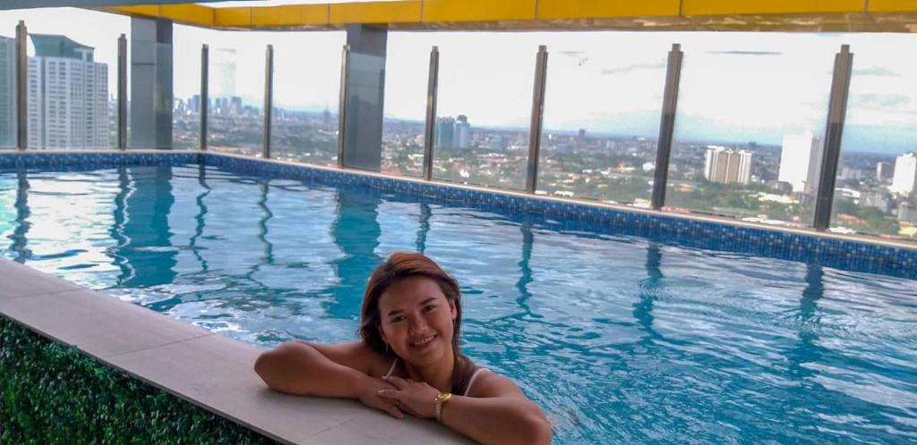 Eine Frau, die in einem Pool auf einem Wolkenkratzer liegt. in der Unterkunft Studio Service Apartment 2guests allows stay up to 5guests 19055 in Manila