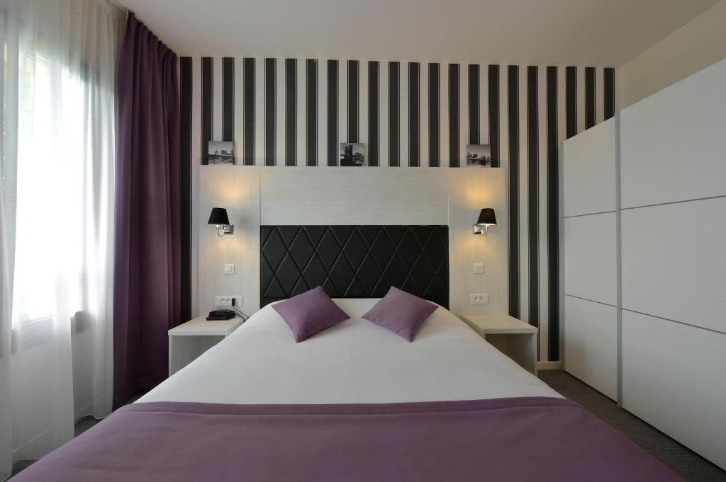 a bedroom with a large white bed with purple pillows at Auberge de l'Etoile in Thoiry