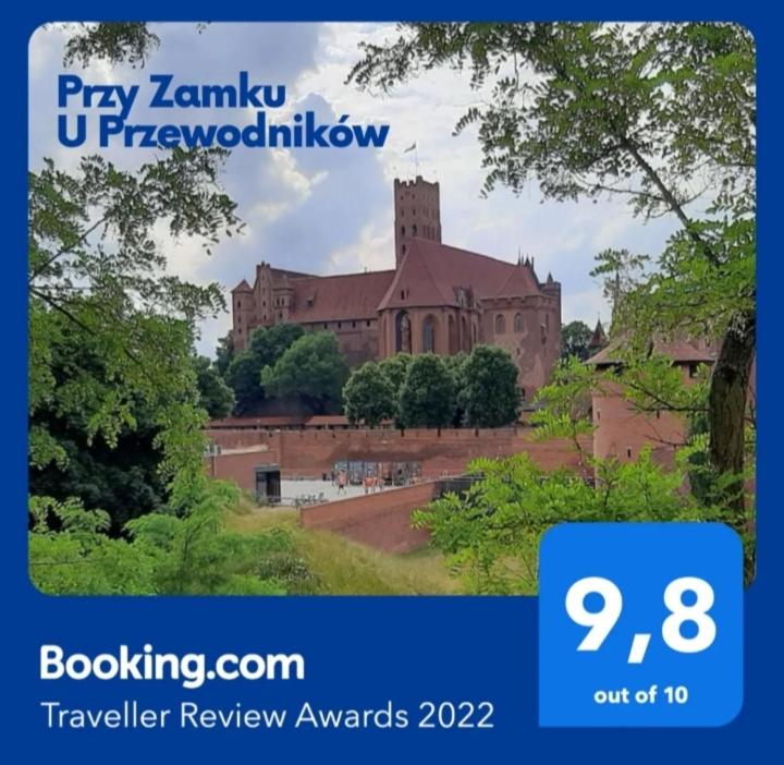 マルボルクにあるPrzy Zamku U Przewodnikówの時計塔のある大きなレンガ造りの建物の写真