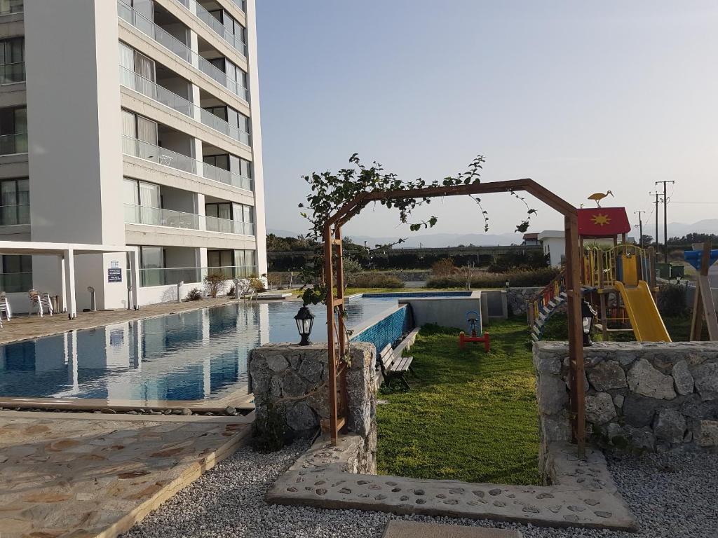 un parque infantil frente a un edificio con piscina en Apartaments Aphrodite, en Ghaziveran
