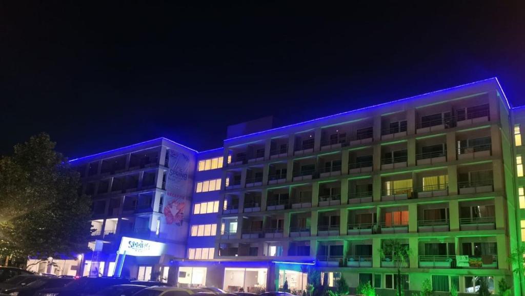 un edificio con luces azules por la noche en Spring Holiday Resort en Neptun