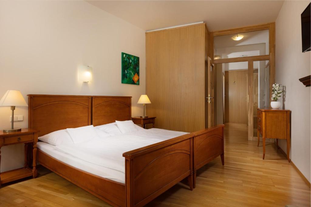 Un dormitorio con una gran cama de madera con sábanas blancas. en OREA Hotel Arigone Olomouc, en Olomouc
