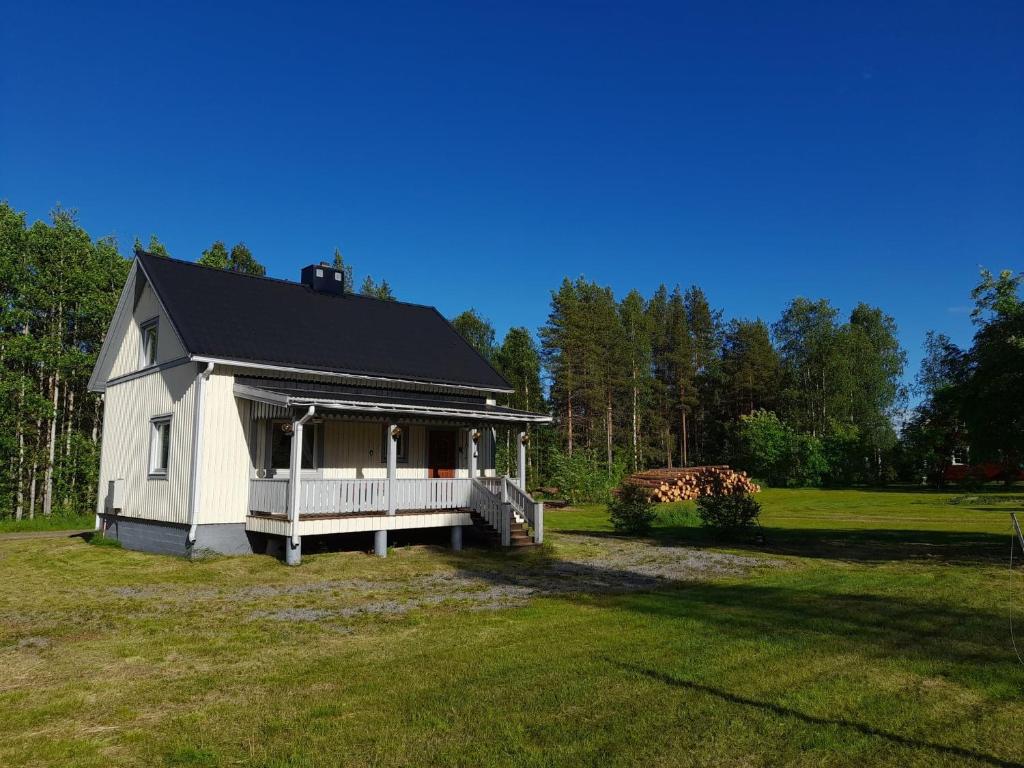 a small white house on a grass field at House next door the Arctic Circle in Överkalix