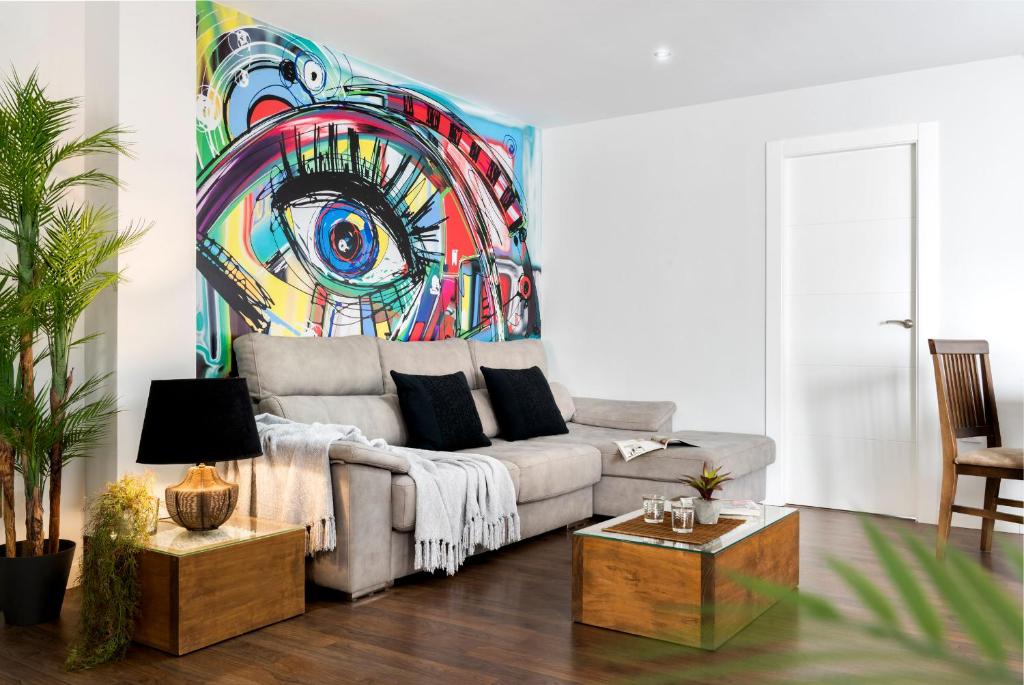 una sala de estar con sofá y una pintura en la pared en Viviendas con Fines Turísticos "Quivir Pidal" en Andújar