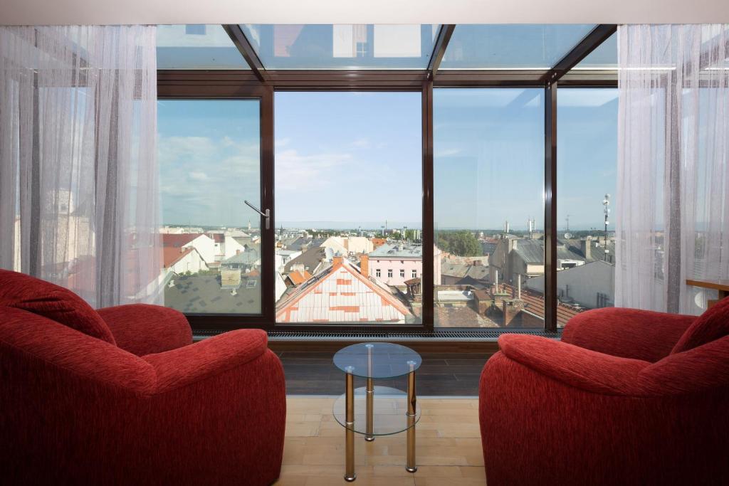 sala de estar con 2 sillas y ventana grande en OREA Hotel Arigone Olomouc, en Olomouc