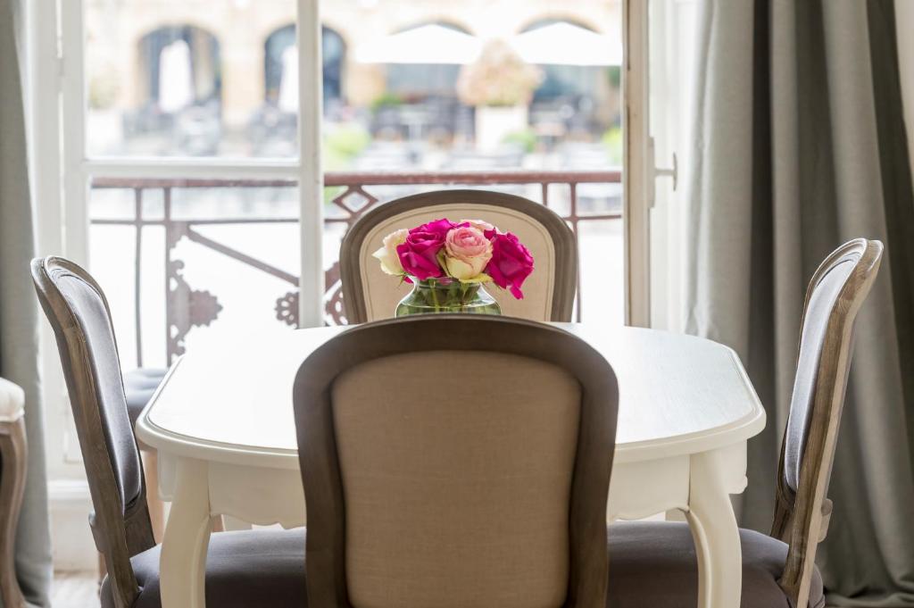 une table et des chaises avec un vase de fleurs. dans l'établissement Suites Mana - Suite Bleu Pacifique - Place Ducale avec Parking privé inclus, à Charleville-Mézières