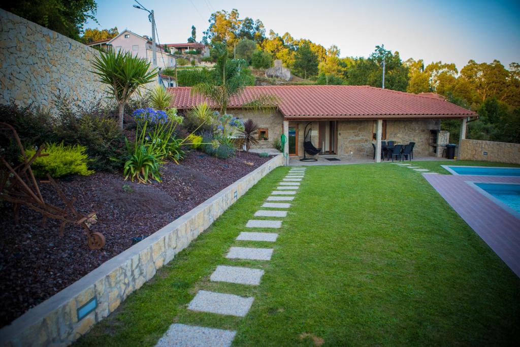 um jardim com um caminho de pedra em frente a uma casa em DreamVille - Casa da Tapada em Arcos de Valdevez