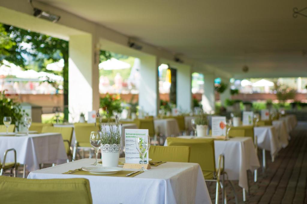 an empty restaurant with white tables and chairs at Rixos-Prykarpattya Resort in Truskavets