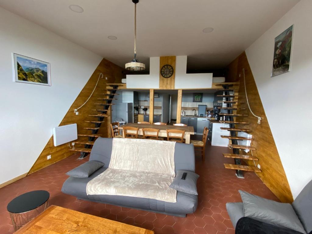 a living room with a couch and a spiral staircase at appartement 8 couchages au lioran rando vtt ski in Le Lioran