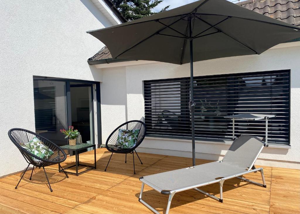 patio z 2 krzesłami i parasolem w obiekcie Apartment Living w mieście Schwabach