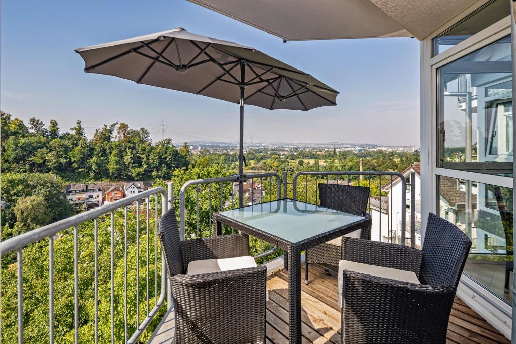 einen Balkon mit einem Tisch, Stühlen und einem Sonnenschirm in der Unterkunft Koblenz Rheinblick Appartement in Vallendar