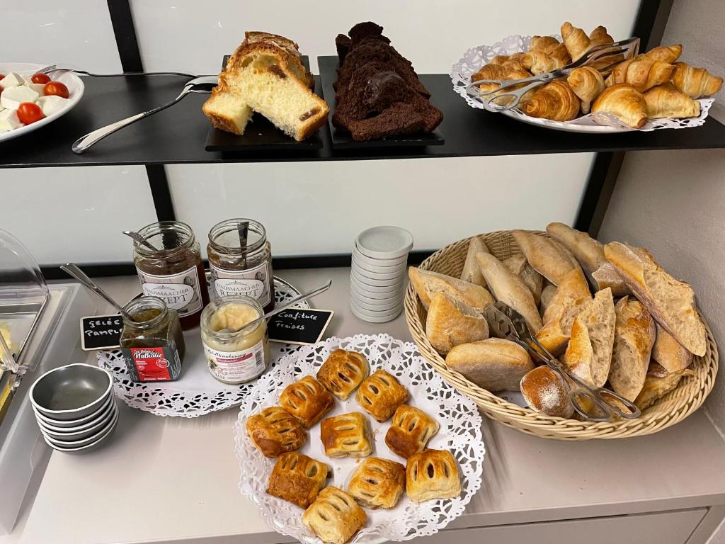 a table with various types of bread and pastries at Hotel Monvillage in Mondercange