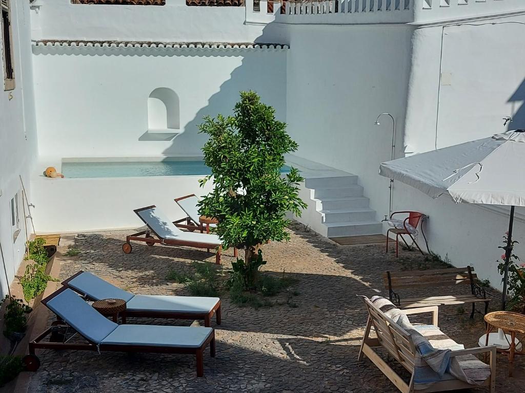 un patio con sillas, un árbol y una piscina en Casa Ancha, en Beja