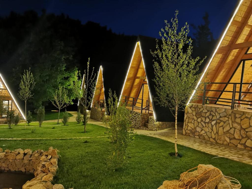a house with a stone wall and trees in a yard at Valea cu Dor Verde in Pîrscov