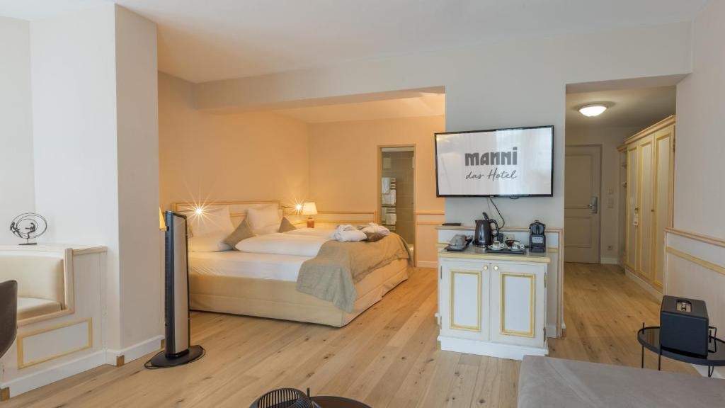 a bedroom with a bed and a flat screen tv at MANNI das Hotel in Mayrhofen