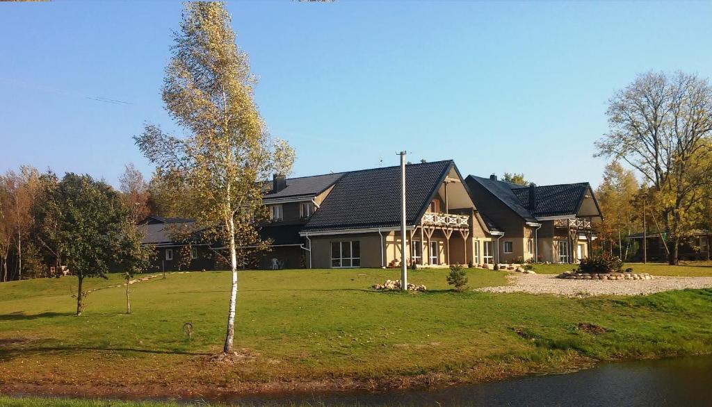 een groot huis met een boom ervoor bij Villa Cheval in Aukštadvaris