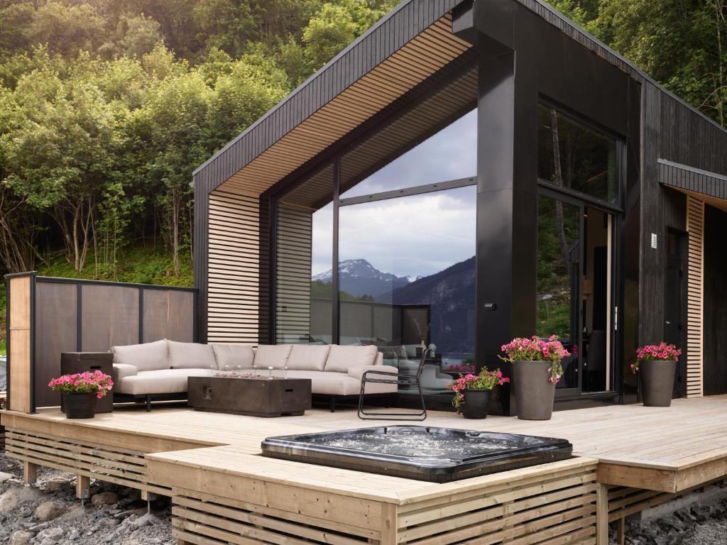 a black house with a hot tub on a deck at Koie Deluxe in Stranda