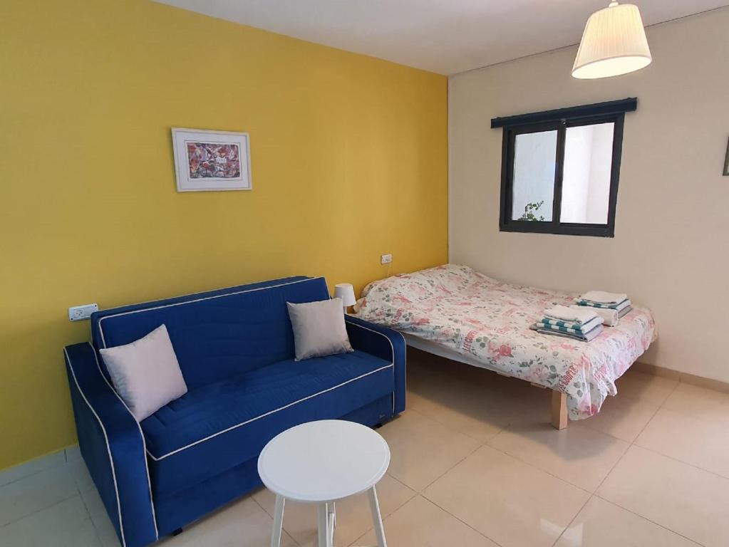 sala de estar con sofá azul y cama en יחידת דיור עם בריכה פרטית מפנקת, en Rosh Pina