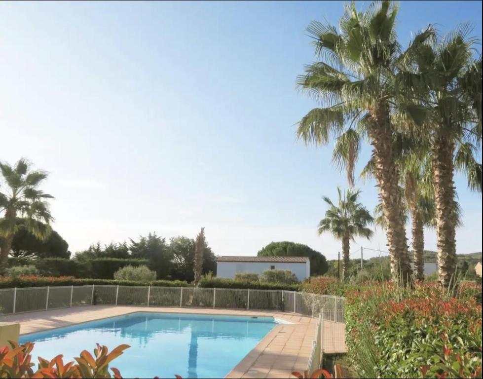 una piscina con palme sullo sfondo di L’AZUREENNE - 2/4 Pers Cosy, spacieux avec piscine a La Seyne-sur-Mer