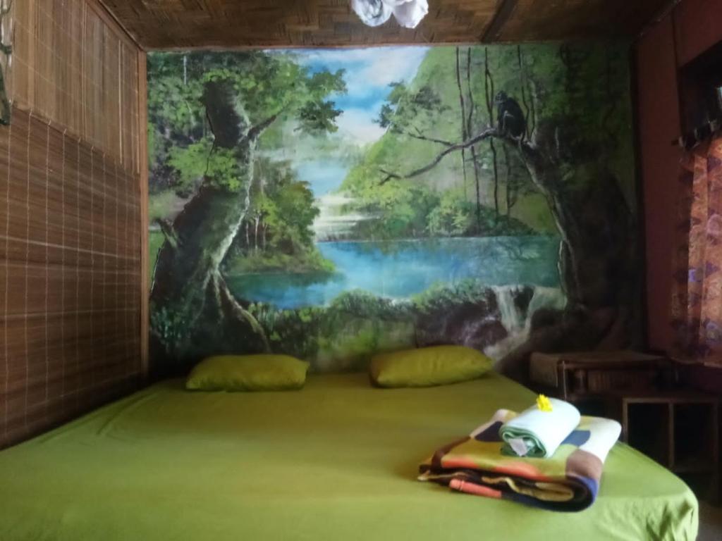 una camera da letto con un dipinto sul muro di Lucky Bamboo'Bungalows-Resto and Orangutan Jungle Trekking Tours a Bukit Lawang